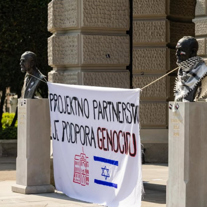 Slika s majskega protesta LDŠ pred rektoratom Univerze v Ljubljani. Na sliki je za doprsna kipa obešena zastava, na kateri piše "Projektno partnerstvo je podpora genocidu". Pod napisom sta narisana logotip Univerze v Ljubljani in izraelska zastava.